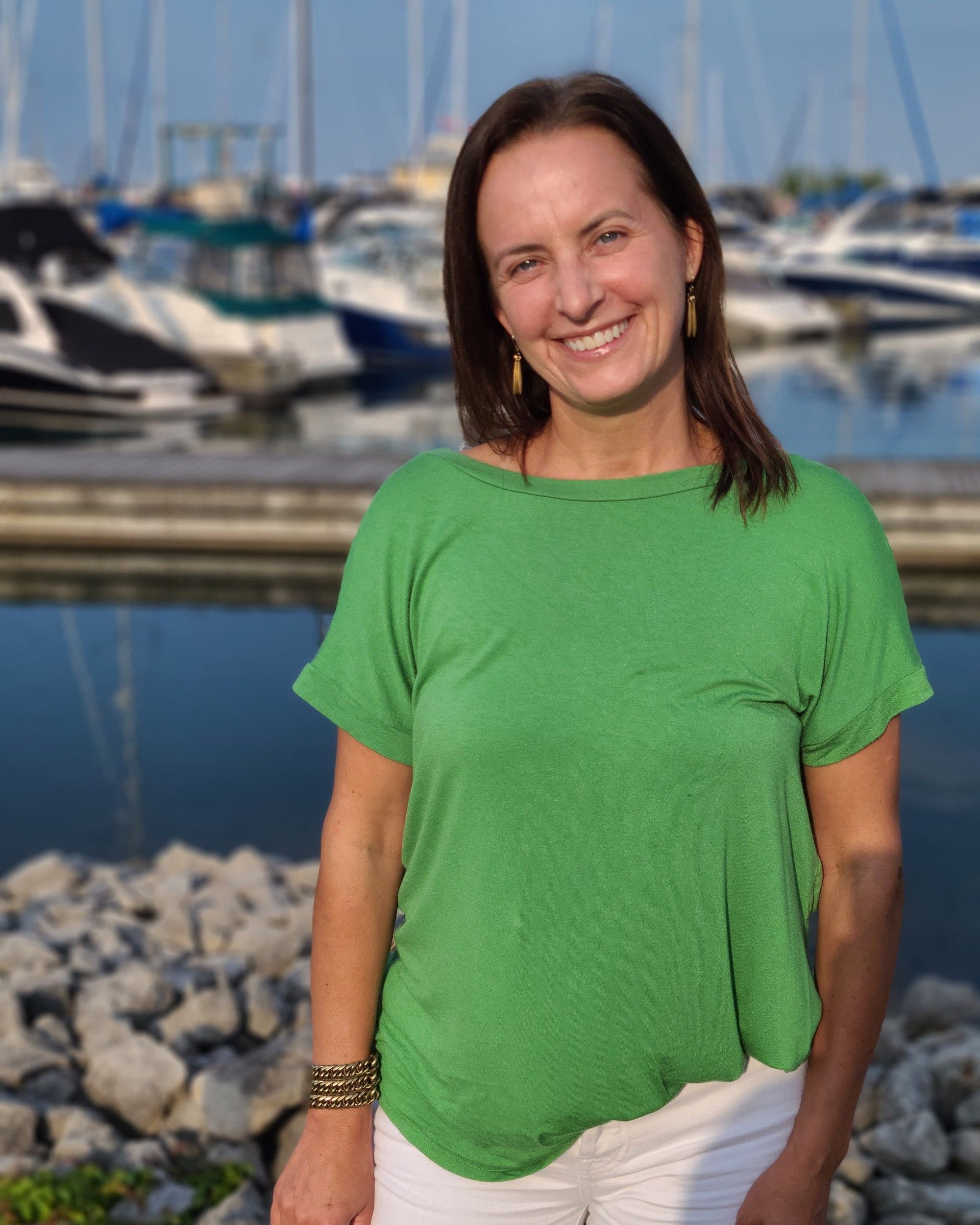 Louise standing outdoors at a marina in warm evening light